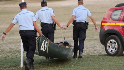 Trois policiers transportent le cano&euml; des quatre touristes disparus pr&egrave;s du lac de Sainte-Croix, dans le Verdon, le 16 ao&ucirc;t 2013. (FRANCK PENNANT / AFP)