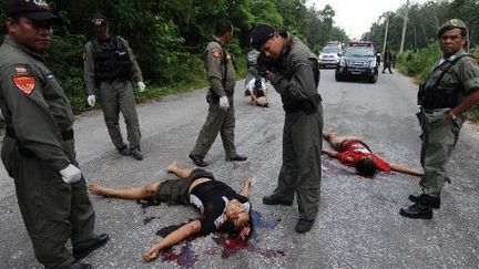 Des policiers thaïlandais inspectent le site où deux paramilitaires ont été tués dans le district de Ra-Ngae, au centre de la  province de Narathiwat, le 9 octobre 2012. La police soupçonne les militants séparatistes qui sévissent dans cette région. (AFP PHOTO / Madaree Tohlala)