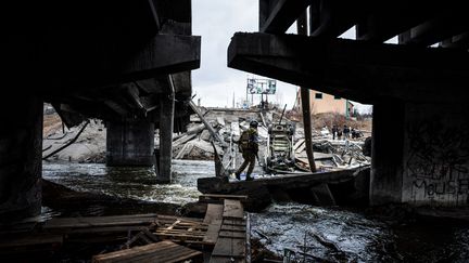 Un soldat ukrainien progresse dans les ruines de la ville d'Irpin (Ukraine), dimanche 13 mars 2022. (DIMITAR DILKOFF / AFP)