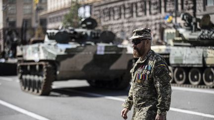 Un soldat ukrainien devant des tanks russes&nbsp;saisis par l'Ukraine, à Kiev, le 24 août 2022. (METIN AKTAS / ANADOLU AGENCY / AFP)