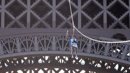 L'athlète Stéphane Diagana sur une tyrolienne installée depuis le premier étage de la Tour Eiffel lors du relais de la flamme olympique avant les Jeux d'Athènes, le 25 juin 2004. (PIERRE VERDY / AFP)