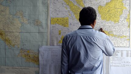 Un homme regarde une carte de la zone de recherches du vol QZ8501 d'AirAsia, disparu le 28 d&eacute;cembre 2014 lors de son trajet entre l'Indon&eacute;sie et Singapour. (MANAN VATSYAYANA / AFP)