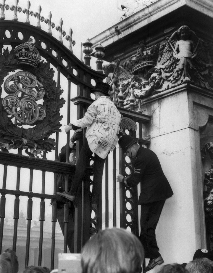 En Beatles-fan klatrer gjennom portene til Buckingham Palace under det legendariske popbandets besøk til dronning Elizabeth II i 1965.  (SENTRAL PRESSE / AFP)