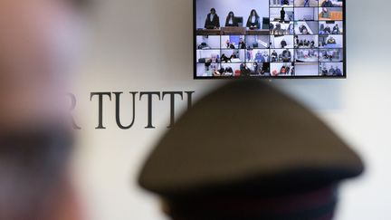 A courtroom monitor shows defendants listening to the verdict of the mafia trial in Lamezia Terme on November 20, 2023. (GIANLUCA CHININEA / AFP)