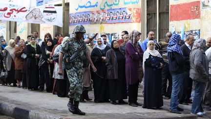 Des Egyptiens patientent devant un bureau de vote sous la surveillance de l'arm&eacute;e au Caire (Egypte), le 28 novembre 2011. (AHMED JADALLAH / REUTERS)