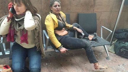 Deux femmes, hagardes, après&nbsp;la double explosion qui a visé l'aéroport de Bruxelles à Zaventem (Belgique), le 22 mars 2016. Trois attentats-suicide, revendiqués par l'organisation Etat islamique, ont tué ce jour-là 32 personnes dans la capitale belge. (KETEVAN KARDAVA / GEORGIAN PUBLIC BROADCASTER / AFP)