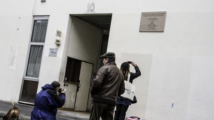 Des passants prennent en photo la plaque en hommage aux victimes des attentats à "Charlie Hebdo", à Paris, le 5 janvier 2016. (YANN KORBI / CITIZENSIDE.COM / AFP)