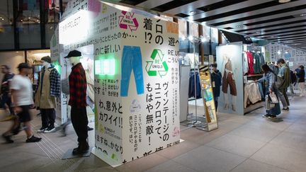 Clients parcourant les articles vendus dans le cadre du projet de vêtements d'occasion Uniqlo dans la boutique Harajuku de la marque à Tokyo, le 17 octobre 2023 (KAZUHIRO NOGI / AFP)