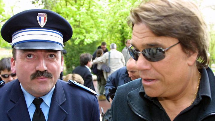 Sous la protection d'un policier, il se rend, le 12 avril 2003 &agrave; Cognac, &agrave; la projection, du t&eacute;l&eacute;film "Commissaire Valence",&nbsp;dans le cadre du 21e festival du film policier. (PATRICK BERNARD / AFP)