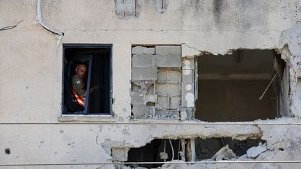 Un homme inspecte un bâtiment endommagé par une roquette tirée depuis le Liban à Kiryat Ata, dans le district israélien de Haïfa, le 19 octobre 2024. (JACK GUEZ / AFP)