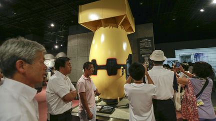 Des visiteurs observent une r&eacute;plique de la bombe atomique qui s'est abattu sur la ville de Nagasaki (Japon) en 1945, samedi 8 ao&ucirc;t 2015.&nbsp; (KIMIMASA MAYAMA / MAXPPP)