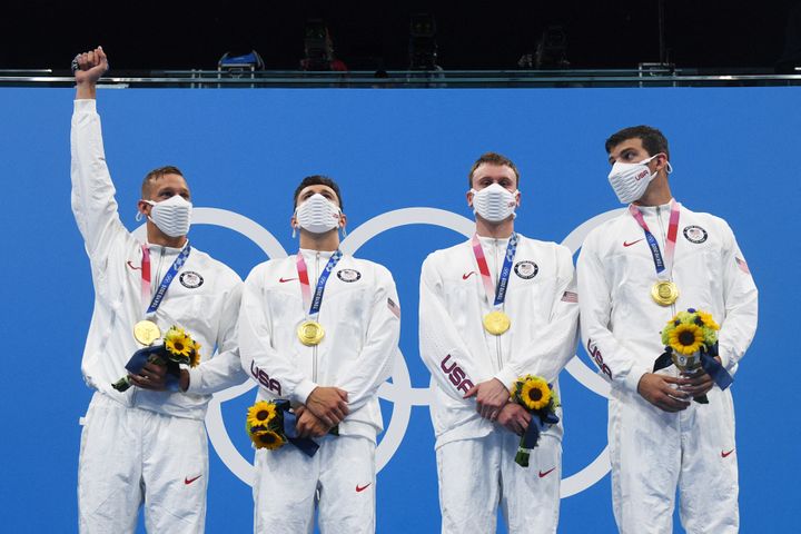 Caeleb Dressel (à gauche) lève le poing sur le podium après sa médaille d'or au relais 4x100m nage libre avec&nbsp;Blake Pieroni, Bowen Becker&nbsp;et Zach Apple. (OLI SCARFF / AFP)