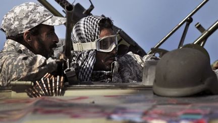 Des insurgés libyens protègent le départ de leurs troupes vers le port pétrolier de Ras Lanouf, le 27 mars 2011 (AFP/ARIS MESSINIS)