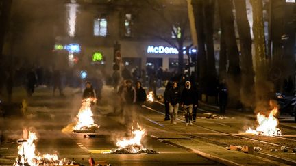 Des opposants à la réforme des retraites défilent au milieu de détritus incendiés, lundi 20 mars 2023 à Lyon (Rhône). (JEFF PACHOUD / AFP)