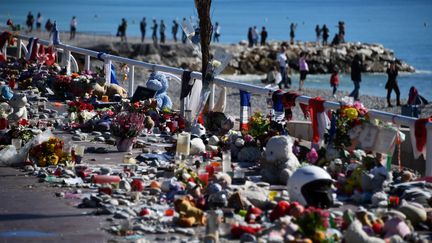 Cette photo prise le 15 octobre 2016, montre des bougies, des jouets et des fleurs déposés sur la promenade des Anglais, à Nice, à l'occasion d'un hommage aux victimes&nbsp;de l'attaque terroriste dans laquelle un camion a foncé dans la foule qui assistait aux fêtes du 14 juillet.&nbsp; (ANNE-CHRISTINE POUJOULAT / AFP)