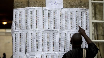 Un Malien tente de retrouver son nom sur une liste d'&eacute;lecteurs de la pr&eacute;sidentielle malienne, &agrave; l'ambassade du Mali, &agrave; Paris, le 11 ao&ucirc;t 2013. (KENZO TRIBOUILLARD / AFP)