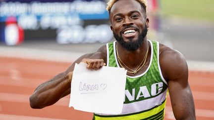 Le sprinteur français Mickael Zeze montre une pancarte avec le nom de son fils, "Liam", après sa victoire sur l'épreuve de 200 mètres aux championnats de France de Caen, le 26 juin 2022. (SAMEER AL-DOUMY / AFP)