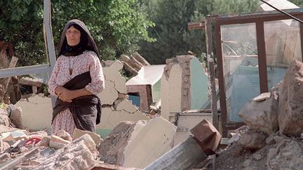 Une femme sur les ruines d'un immeuble détruit par le tremblement de terre qui a secoué l'Iran le 21 juin 1990. (AFP / Joel Robine)