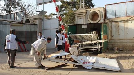 Des employ&eacute;s afghans de MSF d&eacute;placent la porte d&eacute;truite de l'enceinte de leur h&ocirc;pital &agrave; Kunduz (Afghanistan), le 15 octobre 2015. (NAJIM RAHIM / AP / SIPA)