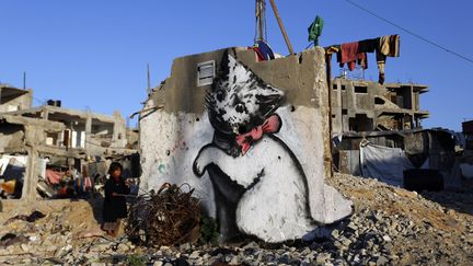 Un chaton peint sur un pan de mur, parmi les ruines de Gaza, près d'un enfant. Un moyen comme un autre d'attirer l'attention du monde sur une enclave dévastée par la guerre.
 (Mohammed Abed / AFP)