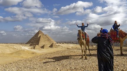 Des touristes font la pose devant les pyramides de Menkaure, Chephren et Kheops à&nbsp;Gizeh, au Caire.&nbsp; (MATTES RENE / HEMIS.FR / HEMIS.FR)