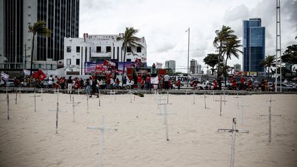 Plusieurs croix sont placées sur la plage à&nbsp;Recife au Brésil, samedi 23 janvier 2021, lors d'une manifestation contre le gouvernement Bolsonaro. (PAULO PAIVA / AGIF / AFP)