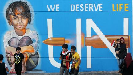 Des Irakiens devant une peinture murale, place Tahrir à Bagdad, le 8 novembre 2019. (AHMAD AL-RUBAYE / AFP)