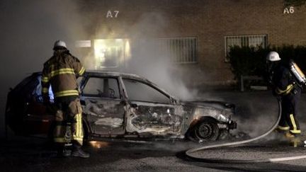 Des pompiers éteignent un incendie de voiture après les émeutes, à Husby, banlieue de Stockholm, le 21 mai 2013. (AFP/JONATHAN NACKSTRAND)