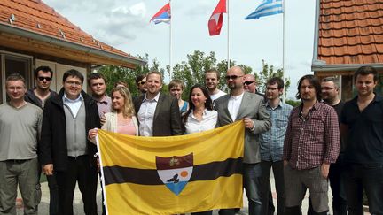 Le président autoproclamé de la «République libre du Liberland» Vit Jedlička (au centre, en costume vert foncé) pose avec son épouse, quelques-uns de ses futurs concitoyens et le drapeau de la nouvelle micronation. Bački Monoštor, Serbie, 1er mai 2015. (REUTERS/Antonio Bronic TPX IMAGES OF THE DAY )