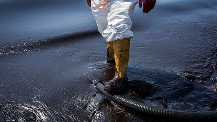 Un employé de la mairie d'Athènes (Grèce) nettoie une plage souillée par les hydrocarbures après le naufrage d'un tanker, le 14 septembre 2017.&nbsp; (KOSTIS NTANTAMIS / NURPHOTO / AFP)