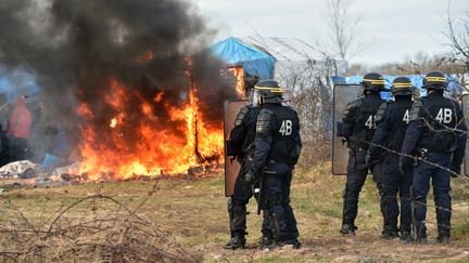 "Jungle" de Calais : cabanes et les tentes démantelées et brûlées devant les migrants et un cordon de CRS