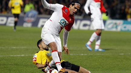 Soner Ertek tacle Radamel Falcao lors d'une rencontre entre Chasselay et Monaco, le 22 janvier 2014. (PHILIPPE MERLE / AFP)