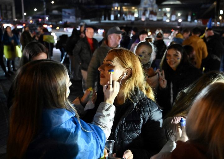 Une manifestante se fait maquiller aux couleurs de l'Ukraine, le 11 novembre 2022 à Kiev (Ukraine). (GENYA SAVILOV / AFP)