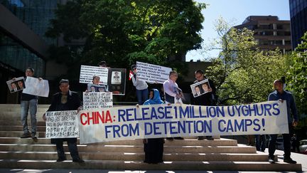 Des personnes brandissent des pancartes pour protester contre le traitement réservé aux Ouïghours par la Chine, à Vancouver (Canada), le 8 mai 2019. (LINDSEY WASSON / REUTERS)