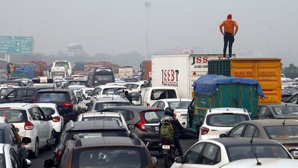 Un homme est monté sur un camion pour regarder l'ampleur d'un embouteillage à l'entrée de New Delhi (Inde). Photo d'illustration. (STR / AFP)