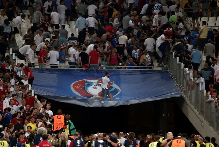 Un homme marche sur une bâche alors que des heurts éclatent au stade Vélodrome, samedi 12 juin, à la fin de la rencontre entre la Russie et l'Angleterre, dans le cadre de l'Euro. (BURAK AKBULUT / ANADOLU AGENCY / AFP)