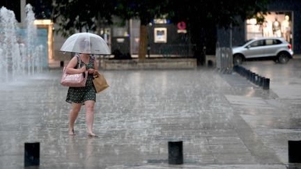 Une femme s'abrite de la pluie à Lons-le-Saunier (Jura), le 11 juillet 2023. (PHILIPPE TRIAS / LE PROGRES / MAXPPP)