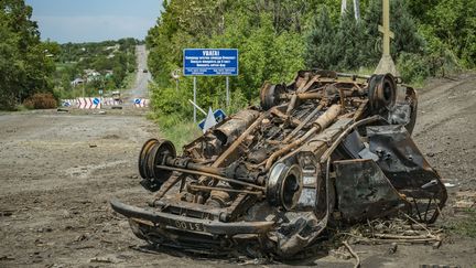 Une voiture détruite sur la route menant au village de Dolnya, dans le Donbass, dans l'est de l'Ukraine, le 2 juin 2022.&nbsp; (CELESTINO ARCE / AFP)