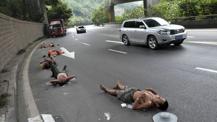 Des ouvriers se reposent &agrave; m&ecirc;me la route &agrave; Chongqing (Chine), le 23 juillet 2013. (SHI TOU / REUTERS)