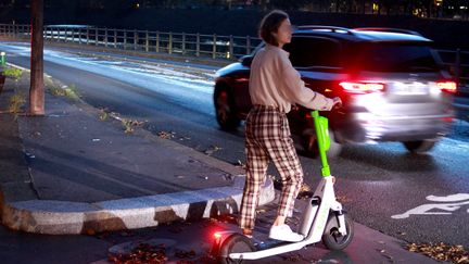 Une jeune femme sur une trottinette à assistance électrique à l'aube dans une rue de Paris. (AURÉLIEN ACCART / RADIO FRANCE)