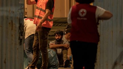 Un survivant du naufrage du bateau, à côté du personnel médical du port de la ville de Kalamata (Grèce), le 14 juin 2023. (ANGELOS TZORTZINIS / AFP)