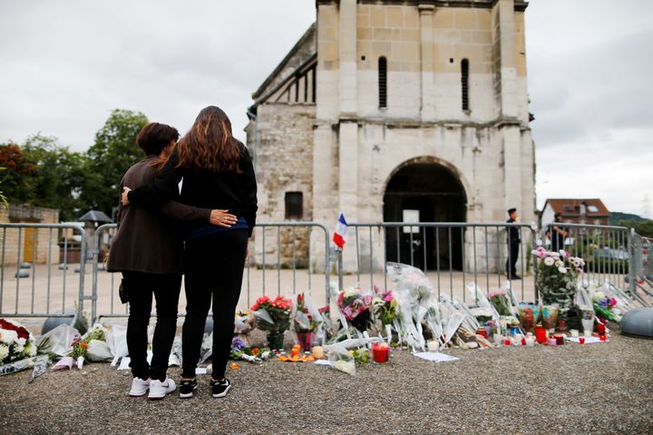 Des anonymes se recueillent devant l'église de Saint-Etienne-du-Rouvray après l'assassinat terroriste du Père Jacques Hamel, le 26 juillet 2016. (CHARLY TRIBALLEAU / AFP)