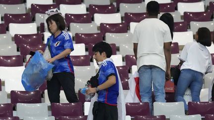 Dans le stade Khalifa International de Doha, les supporters du Japon récupèrent tous les détritus dans les tribunes, pour faire place nette après le match Allemagne-Japon, le 23 novembre 2022. (EUGENE HOSHIKO / AP)