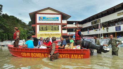 Des rescapés et leurs sauveteurs dans l'Etat de Selangor, en Malaisie, lundi 20 décembre 2021. (ARIF KARTONO / AFP)