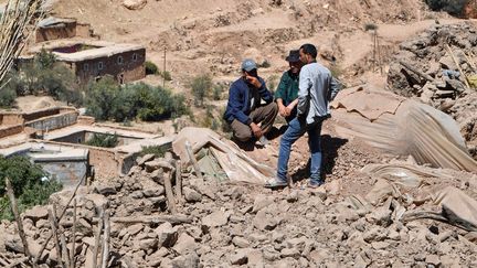 Des habitants marchent sur les décombres des maisons détruites dans le village de Tikht, près d'Adassil, le 10 septembre 2023. (FETHI BELAID / AFP)