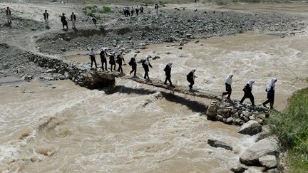 Des &eacute;coli&egrave;res afghanes traversant une rivi&egrave;re &agrave; Qara Zaghan, dans la province de&nbsp;Baghlan (nord de l'Afghanistan). (SHAH MARAI / AFP)