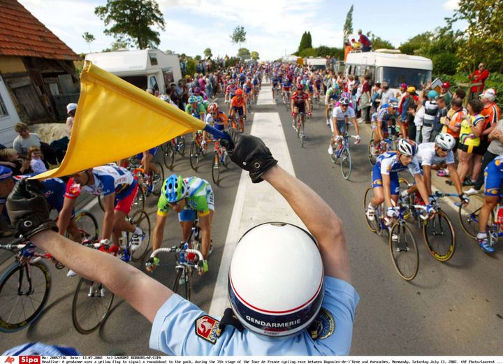 Un gendarme indique la présence d'un rond-point aux coureurs du Tour de France 2002, lors de la 13e étape entre Bagnoles-de-l'Orne (Orne) et Avranches (Manche), le 13 juillet 2002. (LAURENT REBOURS/AP/SIPA / AP)