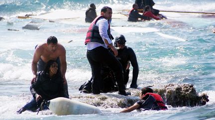 Des membres de secours aident des migrants &agrave; atteindre le rivage sur l'&icirc;le de Rhodes (Gr&egrave;ce), le 20 avril 2015. (ARGIRIS MANTIKOS / EUROKINISSI / AFP)