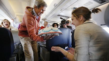 Le secr&eacute;taire d'Etat am&eacute;ricain, John Kerry, apporte un gateau d'anniversaire &agrave; une journaliste de CBS pendant un vol Kaboul-Paris, le 26 mars 2013. (JASON REED / REUTERS)