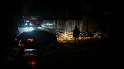 Une personne manche dans une rue de Lviv, plongée dans le noir après de nouvelles frappes russes, le 16 décembre 2022. (YURIY DYACHYSHYN / AFP)